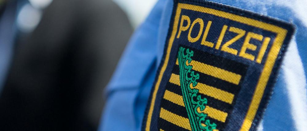 Das Logo der sächsischen Polizei ist an einem Polizeiuniform angebracht.