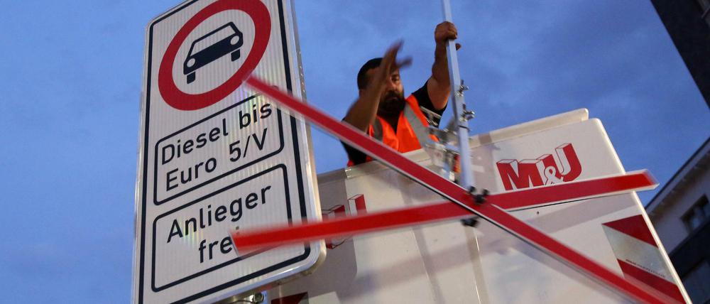 Ein Arbeiter in Hamburg hängt Schilder für ein Fahrverbot auf.
