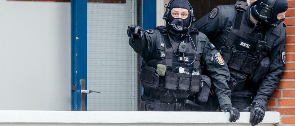 Beamte eines Spezialeinsatzkommando (SEK) der Polizei stehen während einer Razzia vor einer Wohnung.