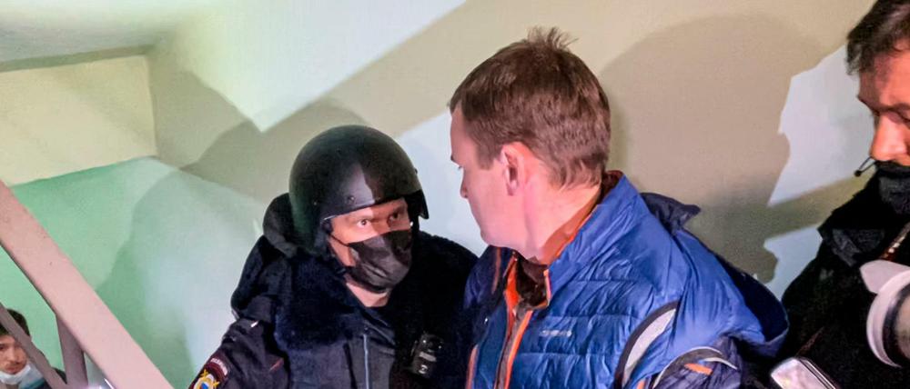 Ein Polizist steht vor Fotografen von einer Tür der Wohnung von Navalnys Bruder.