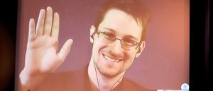 Der NSA-Enthüller Edward Snowden winkt im Dezember 2014 in Berlin während einer Videoschalte dem Publikum zu.