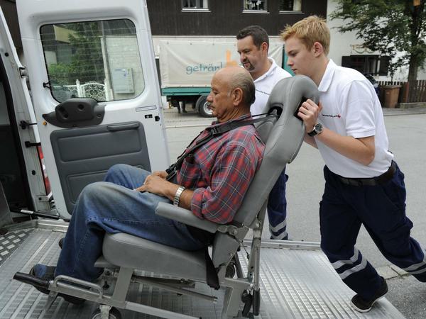 Der Bundesfreiwilligendienstleistende Thomas Volk (r), übt an seinem ersten Arbeitstag, wie man einen Gehbehinderten in einen Transporter schiebt.