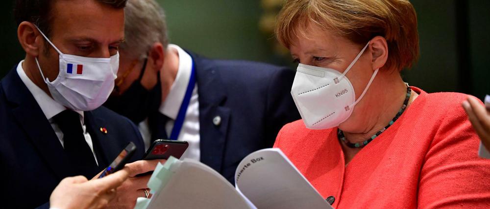 Emmanuel Macron (l), Präsident von Frankreich, fotografiert mit seinem Smartphone Unterlagen ab die Bundeskanzlerin Angela Merkel (CDU) ihm vor einem Treffen am runden Tisch im Rahmen des EU-Gipfels zeigt.