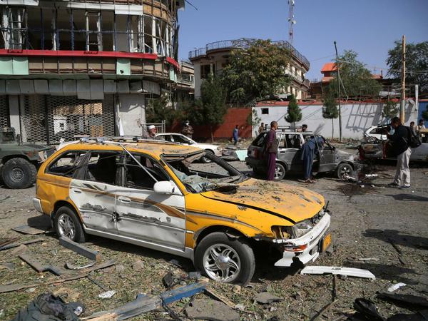Menschen stehen zwischen Trümmern und beschädigten Autos nach der Explosion einer Autobombe in der afghanischen Hauptstadt Kabul.