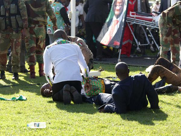 Verletzte werden nach einer Explosion bei einer Wahlkampfveranstaltung des amtierenden Präsidenten Mnangagwa auf dem Rasen liegend verarztet.
