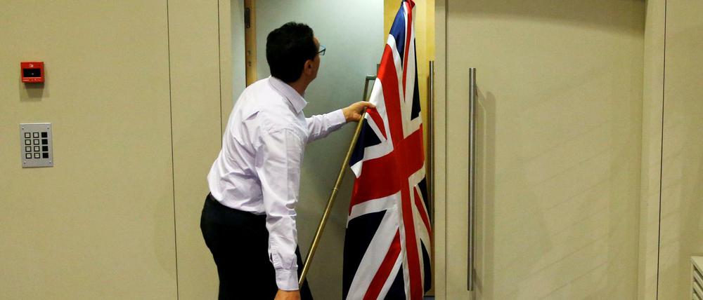 Exit aus der EU. Ein Beamter trägt die britische Flagge aus einem Sitzungssaal in Brüssel hinaus.