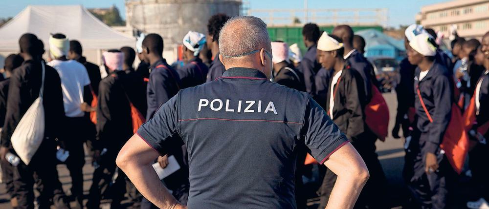 Ein Grenzbeamter beobachtet die Ankunft afrikanischer Flüchtlinge, die mit einem Rettungsboot Italien erreichten.