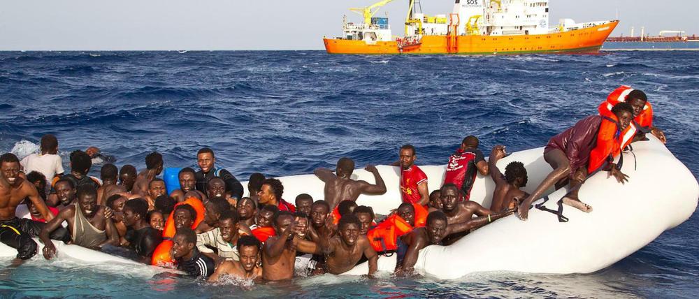 Flüchtlingsboot im Mittelmeer, im Hintergrund Helfer von SOS Mediterranee