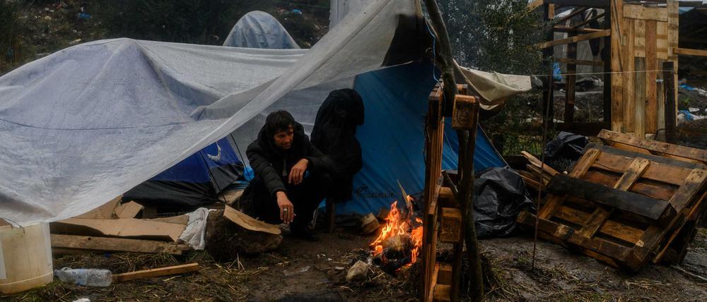 Flüchtling auf Moria. Ein Migrant versucht sich an einem kleinen Feuer in einem provisorischen Lager neben dem Camp Moria auf der griechischen Insel Lesbos aufzuwärmen. 