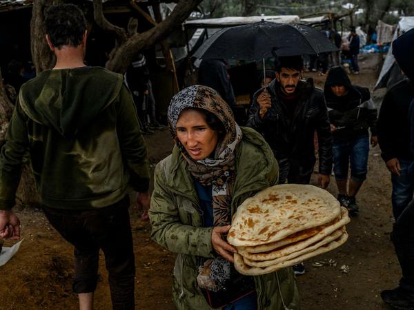Hunger und Regen im Horrorcamp Moria. Eine Frau trägt in einem provisorischen Lager neben dem Camp Moria auf der Insel Lesbos in Griechenland Fladenbrot, die Versorgung des Staates reicht längst nicht für alle Migranten aus. 