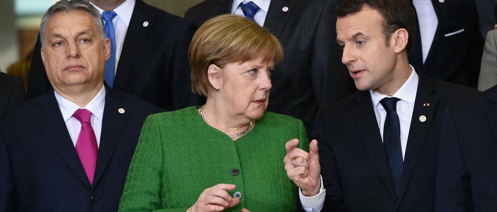 Zugewandt dem einen, im Rücken den anderen. Angela Merkel mit Emmanuel Macron (rechts) und Viktor Orban.