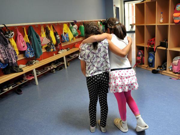 Zwei Mädchen gehen in München Arm in Arm durch ihre Ganztagsschule.
