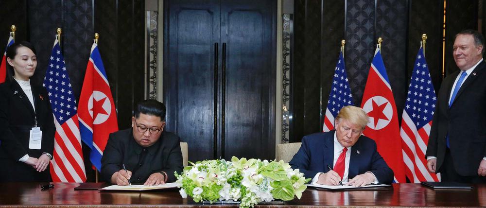 Singapur: U.S. Präsident Donald Trump und der Machthaber von Nordkorea Kim Jong Un unterzeichnen eine gemeinsame Vereinbarung. 