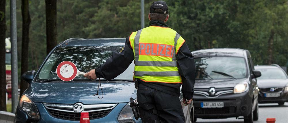 Ein Beamter der Bundespolizei leitet den Einreiseverkehr aus den Niederlanden zur Kontrolle über einen Parkplatz. 