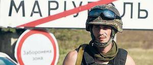 Wer hat das Sagen in der Stadt? Ein ukrainischer Soldat steht vor einem Ortsschild der ostukrainischen Hafenstadt Mariupol. 