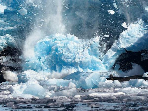 Ein Gletscher auf Grönland kalbt im Sommer. Das Eis in der Arktis schmilzt schneller als von Klimaforschern befürchtet. Das erhöht die globalen Meeresspiegel. 