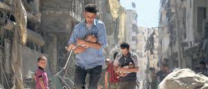 Nach dem Bombardement. Männer haben Babys geborgen und bewegen sich durch die Trümmer von Aleppo. 