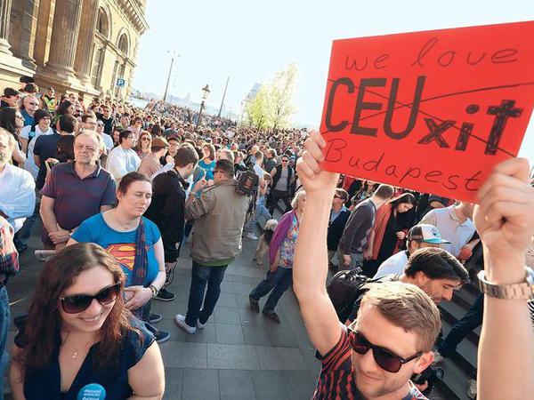 Ein Mann hält bei einer Demonstration ein Plakat mit der Aufschrift "CEUxit" hoch. Der Schriftzug ist durchgestrichen und durch die Worte "We love Budapest" ergänzt.