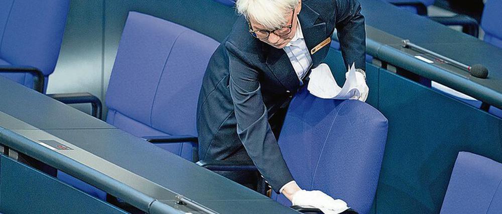 Eine Bundestagsmitarbeiterin desinfiziert in einer Pause die Regierungsbank.