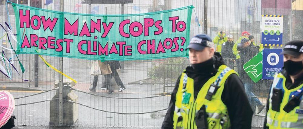 Mit Wortspiel: „Wie viele Cops braucht es, um das Klimachaos wegzusperren?“ Bei der UN-Klimakonferenz in Glasgow, genannt COP 26, kommen die Verhandler der 200 Staaten kaum voran. 