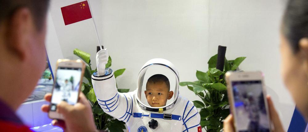 Ein Junge lässt sich in Peking in einer Nachbildung eines chinesischen Astronautenanzugs fotografieren.