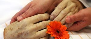 In einem stationären Hospiz in Dessau-Roßlau hält eine Angehörige die Hände ihrer verstorbenen Mutter.