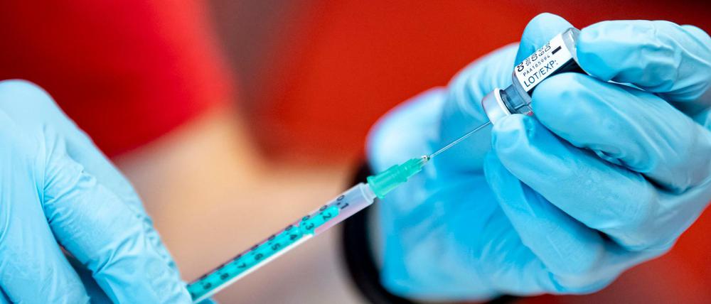 Ein Notfallsanitäter der DLRG zieht an der Universität Potsdam den Corona-Impfstoff von Biontech in eine Spritze.