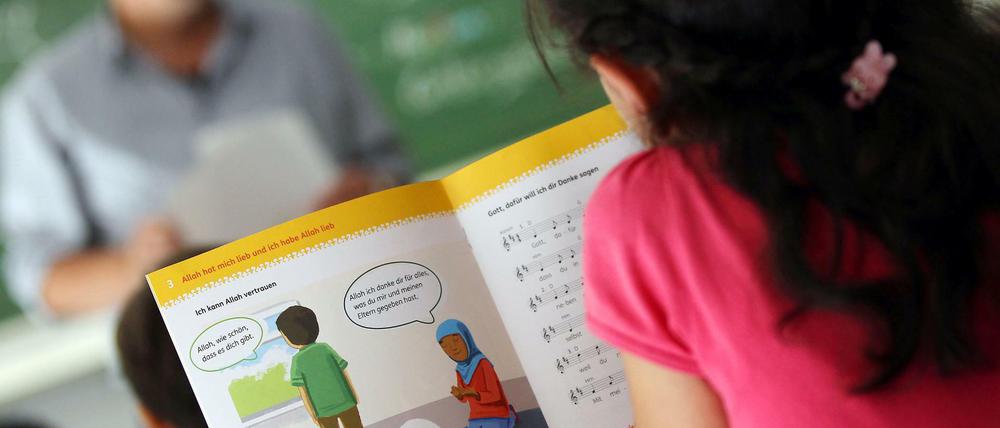 Ein Mädchen liest an einer Bonner Schule während des islamischen Religionsunterrichts in einem Schulbuch.