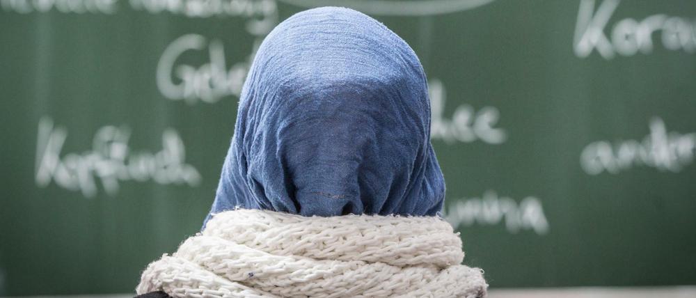 Eine Schülerin mit Kopftuch sitzt im Unterricht.