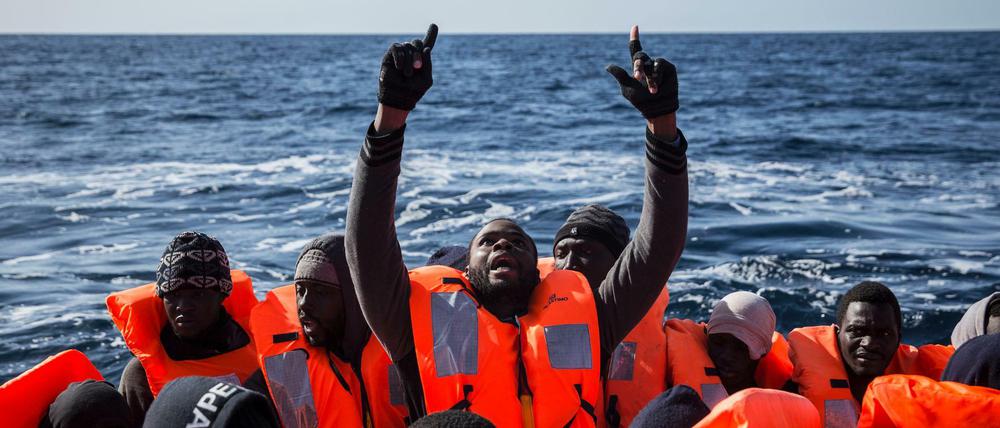 Flüchtlinge aus Afrika sitzen vor der Küste von Libyen in einem Schlauchboot.