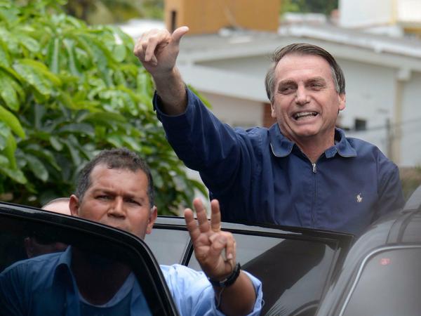 Der künftige brasilianische Präsident Jair Bolsonaro (rechts) winkt vor seinem Haus Anhängern zu.