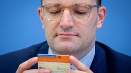Jens Spahn (CDU), Bundesminister für Gesundheit, schaut während der Präsentation der neuen Organspende-Regeln auf einen Organspendeausweis.