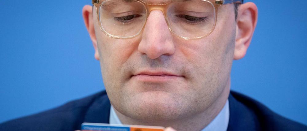 Jens Spahn (CDU), Bundesminister für Gesundheit, schaut während der Präsentation der neuen Organspende-Regeln auf einen Organspendeausweis.