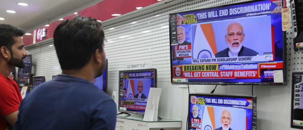 Zwei Inder verfolgen eine Fernsehansprache des indischen Premierministers Narendra Modi in einem Elektronikgeschäft. 