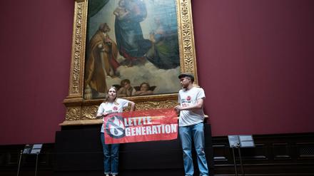 Zwei Umweltaktivist:innen stehen mit einem Banner in der Gemäldegalerie Alte Meister an Raphaels „Sixtinischer Madonna“.