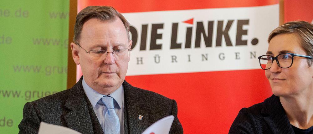 Bodo Ramelow durchblättert den Koalitionsvertrag von Die Linke, SPD und Bündnis 90/Die Grünen, neben ihm sitzt die Linken-Politikerin Susanne Hennig-Wellsow.