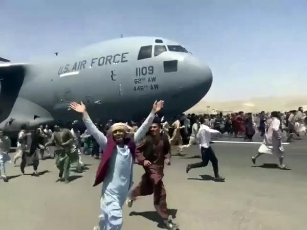 Hunderte Menschen laufen neben einer Boeing C-17 der United States Air Force in Kabul. 