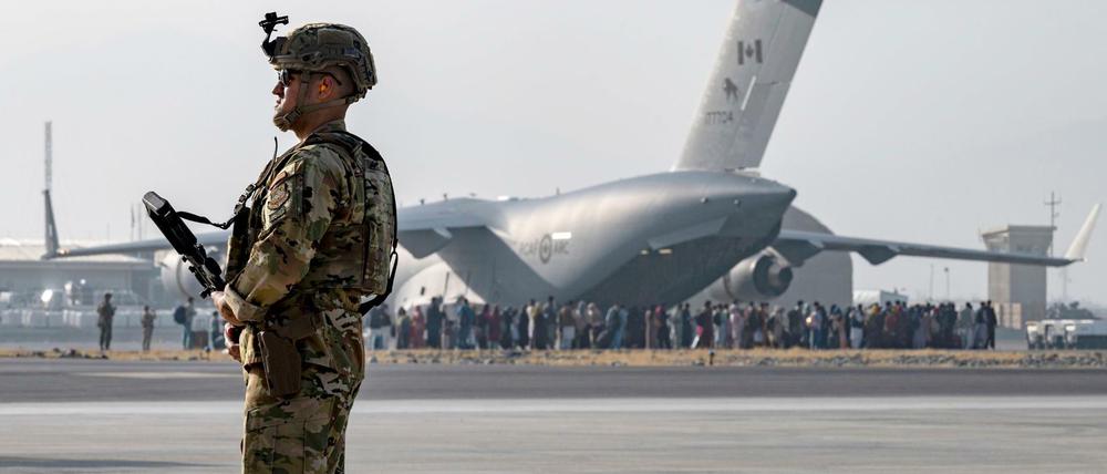 Ein US-Soldat der US-Luftwaffe bewacht die Evakuierte von Nichtkombattanten mit einem Flugzeug vom Typ C-17 Globemaster III.