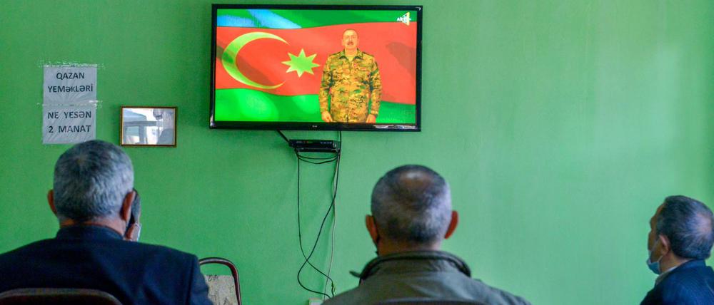 Drei Männer verfolgen in Barda, Aserbaidschan, im Fernsehen eine Ansprache von Ilham Aliyev, Präsident von Aserbaidschan. 
