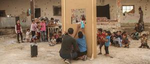 Ein Puppenspiel vor einer zerstörten Schule in Syrien, die vertrieben Kindern als Unterkunft dient. 