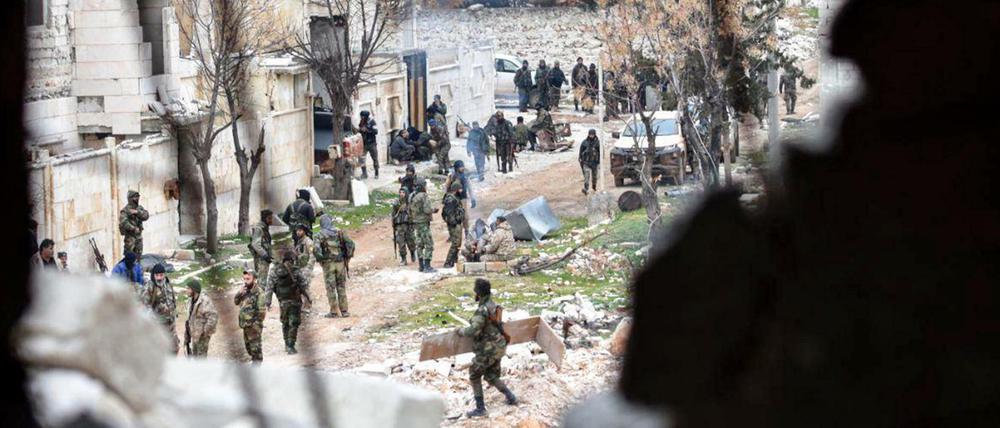 Bewaffnete Soldaten der syrischen Regierung stehen in einer Straße Aleppos. 
