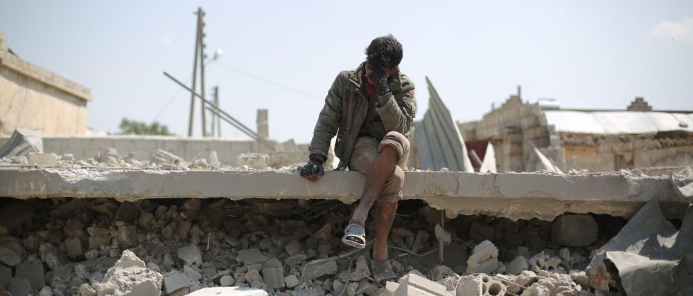 Ein Mann sitzt nach einem Luftangriff zwischen zerstörten Gebäuden in Saraqib.
