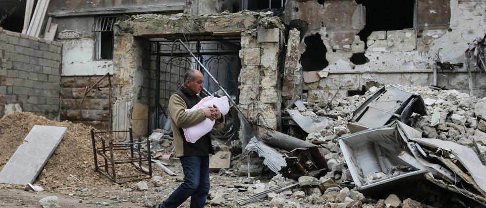 Das im Januar 2017 aufgenommene Foto zeigt einen Mann, der mit seinem Kleinkind im östlichen Stadtteil Salaheddine in der vom Krieg zerstörten Stadt Aleppo unterwegs ist.