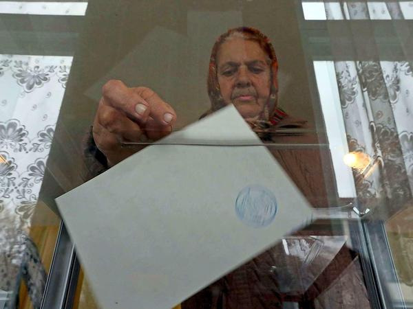 Eine Frau gibt ihren Stimmzettel ab.
