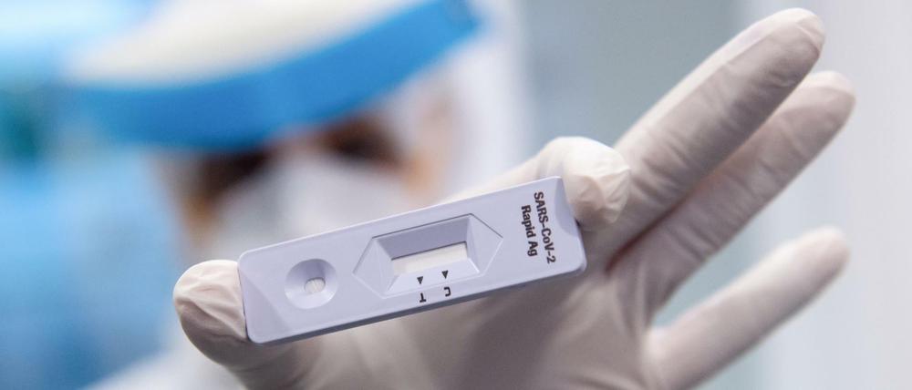 Eine Frau hält am Flughafen München in einem Covid-19 Testcenter einen Antigen-Schnelltest
