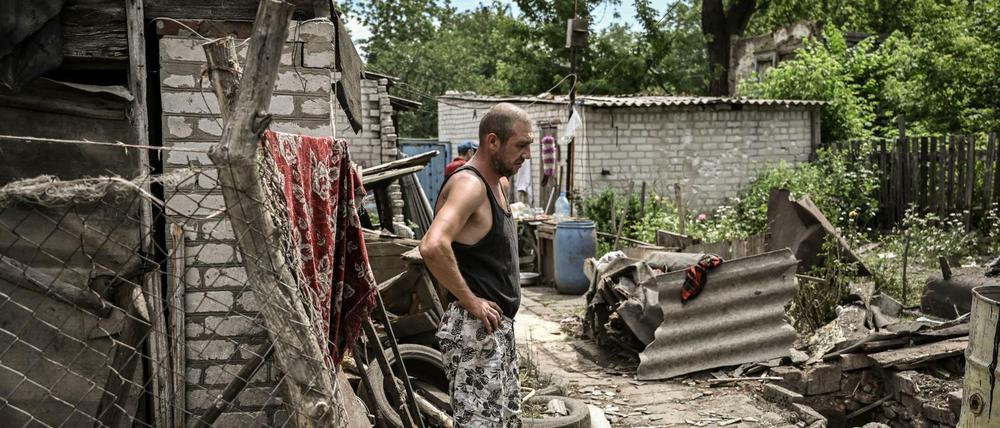 Ein Mann zwischen den Trümmern seines Haus in einem Ort im Donbass