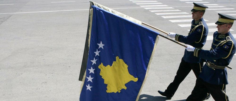 Die Fahne Kosovos von Paradesoldaten am Flughafen in Pristina.