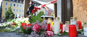 Ein Polizist steht in Würzburg neben Kerzen und Blumen.