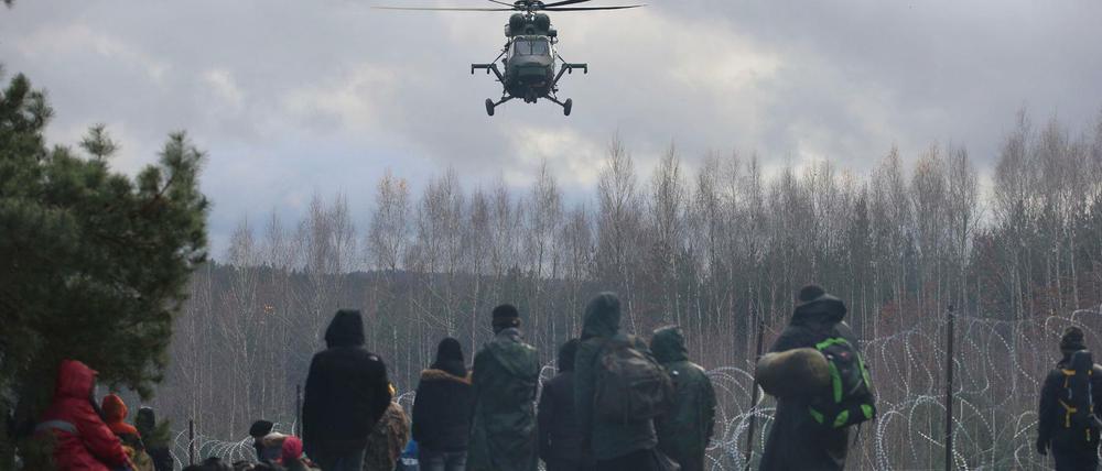 Konfrontation von Humanität und Realität. Tausende Migranten warten in Belarus darauf, die EU-Außengrenze in Polen zu überwinden. Ein polnischer Militärhubschrauber observiert die Szenerie.