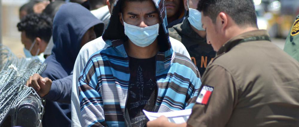 Die Dokumente einer Gruppe von Migranten werden auf mexikanischer Seite an der Grenze überprüft. 